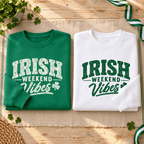 Folded Kelly Green and white sweatshirts showing their contrasting Irish Weekend Vibes graphics