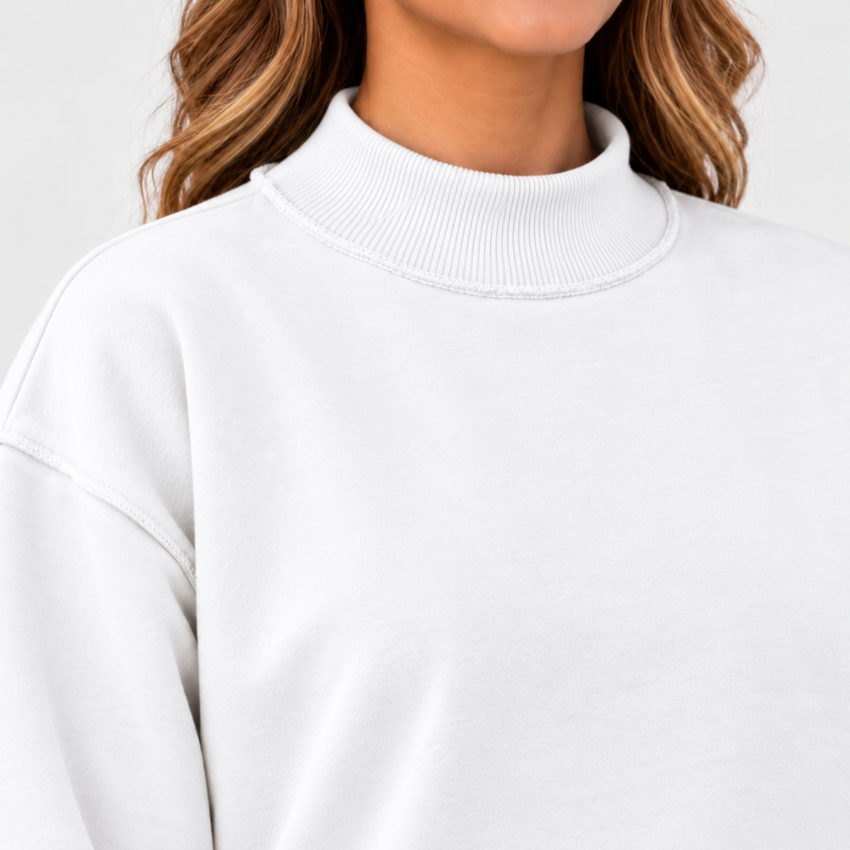 Close-up of women’s white mock neck sweatshirt showing ribbed neckline, exposed seam detail and dropped shoulder construction