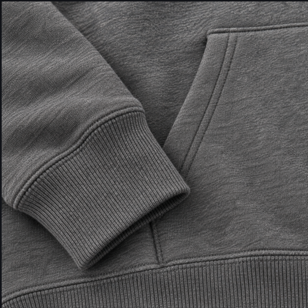 Close-up of a heather gray pullover hoodie showing the ribbed sleeve cuff, ribbed waistband and front kangaroo pocket stitching