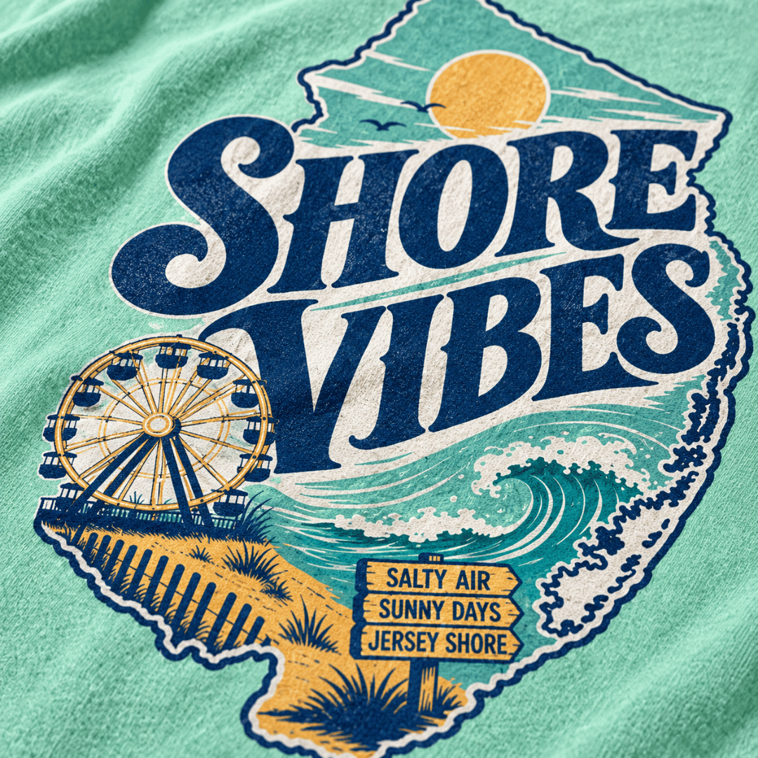 A close-up of a island reef t-shirt featuring a distressed graphic print of the state of New Jersey. The graphic reads 'SHORE VIBES' in large navy blue letters, with a yellow sun, blue ocean waves, a Ferris wheel, and a sandy beach.