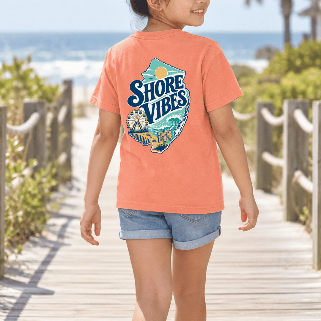 Girl in a Melon orange Shore Vibes t-shirt on a boardwalk path to the beach