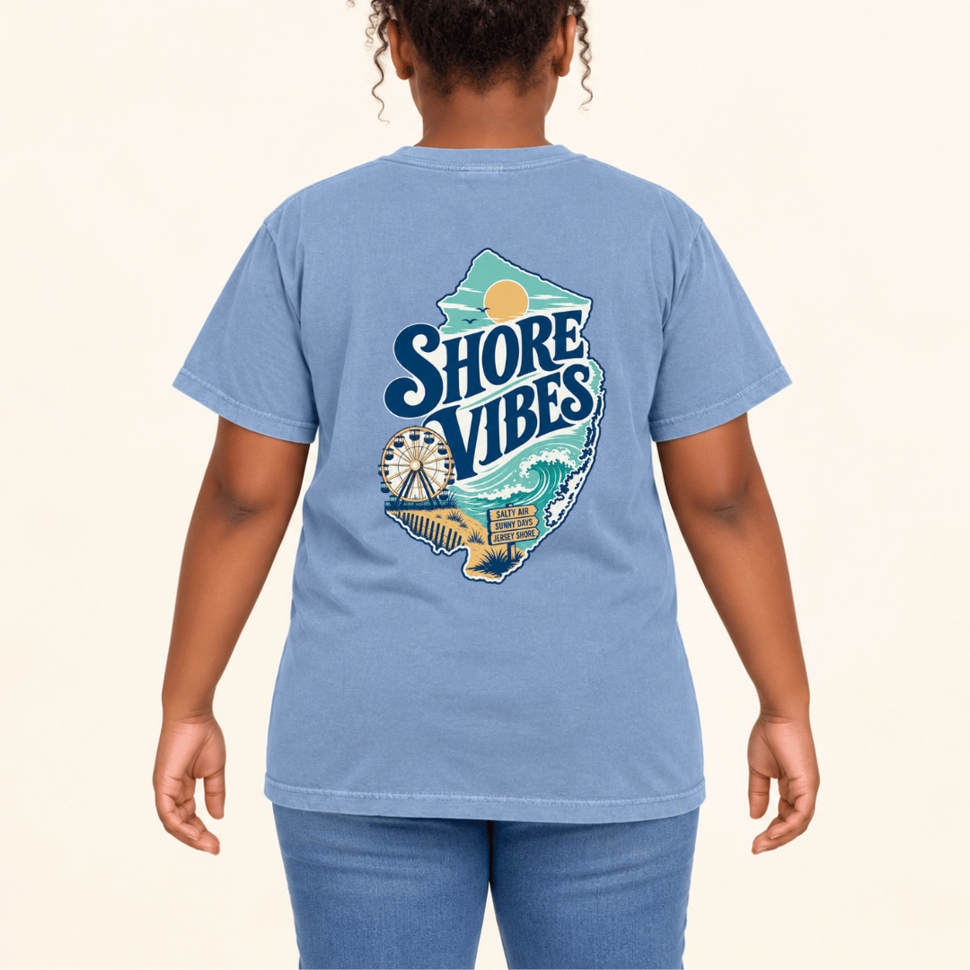 Girl wearing a Washed Denim blue Shore Vibes t-shirt with the back logo, studio photo