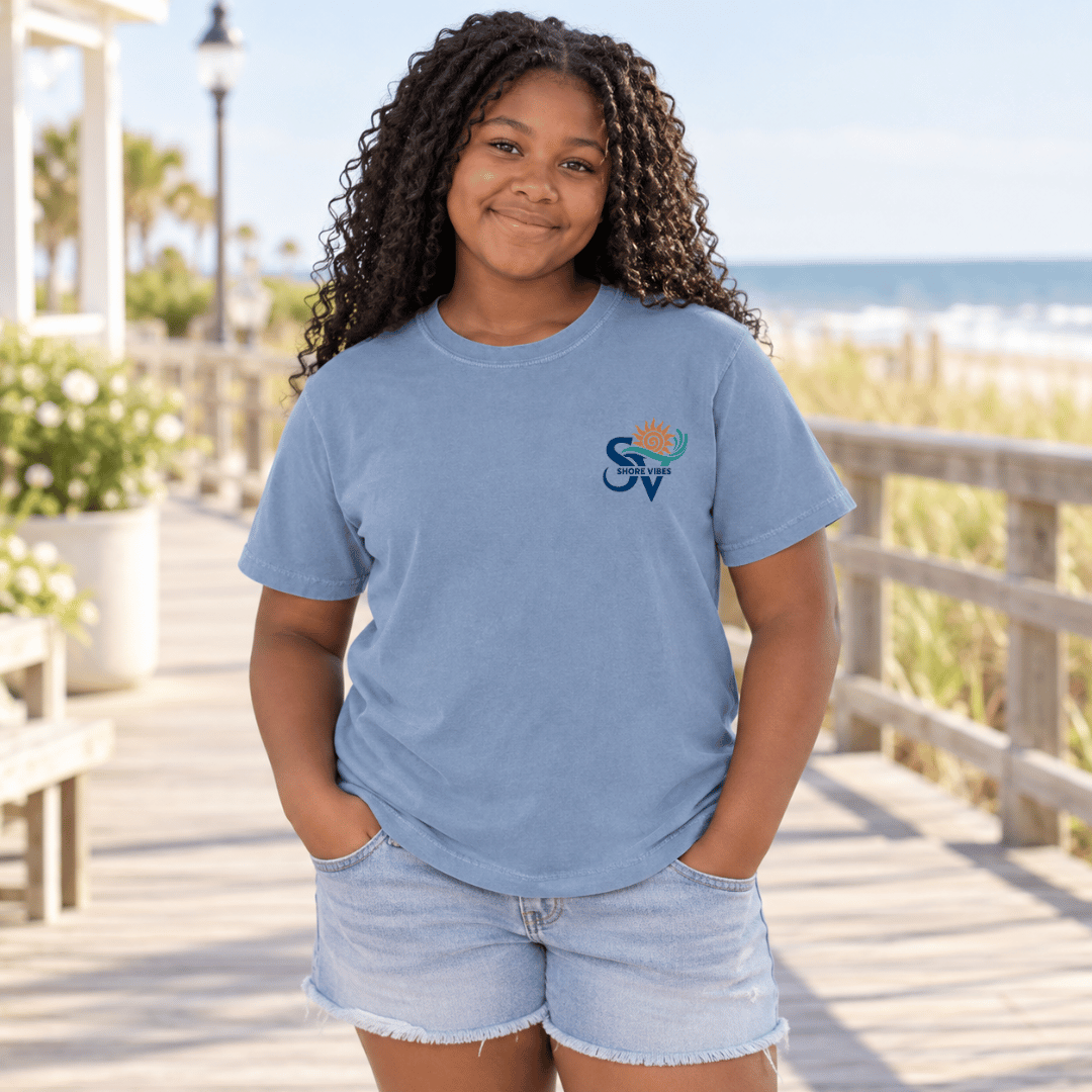 Back view of a girl in a Washed Denim blue Shore Vibes t-shirt showing the full New Jersey coastal graphic, studio photo