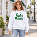 Woman wearing a white Irish Vibes crewneck sweatshirt with a green cursive shamrock design.