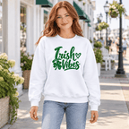 Woman wearing a white Irish Vibes crewneck sweatshirt with a green cursive shamrock design.