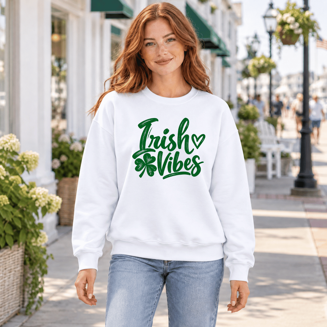 Woman wearing a white Irish Vibes crewneck sweatshirt with a green cursive shamrock design.
