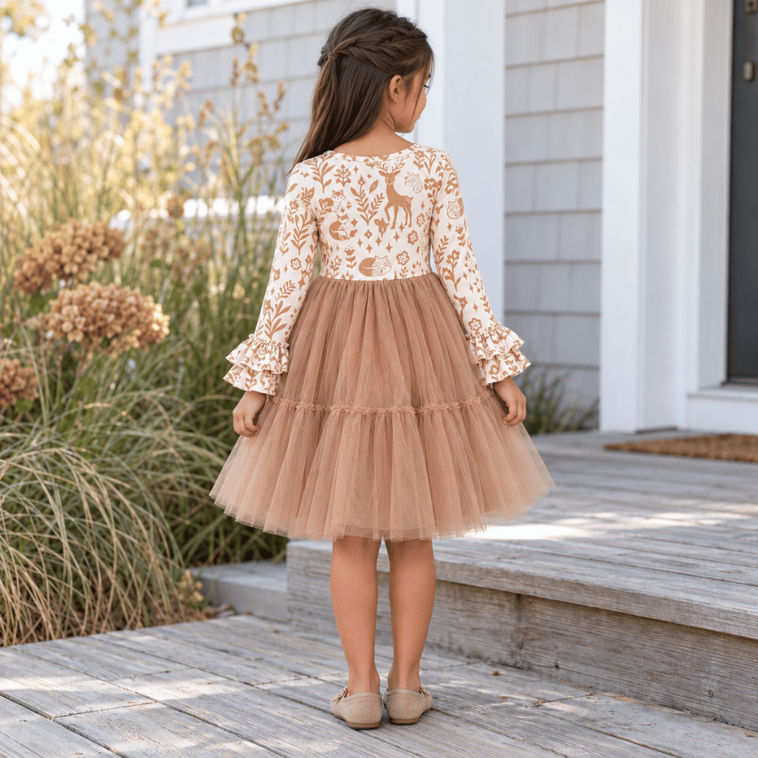 Back view of the woodland print dress showing its long sleeves, gathered waist and tiered tan tulle skirt
