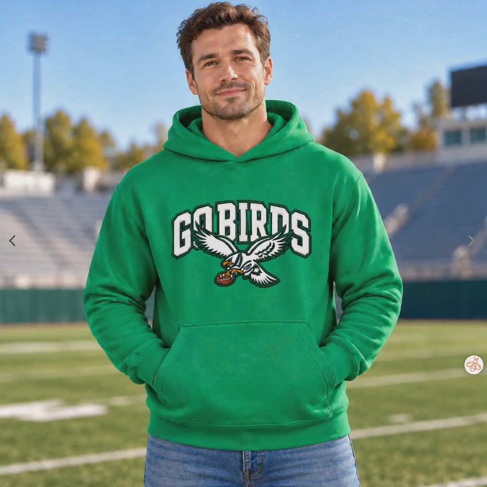 Man wearing a Kelly Green hoodie with white "GO BIRDS" varsity lettering and a flying eagle graphic holding a football